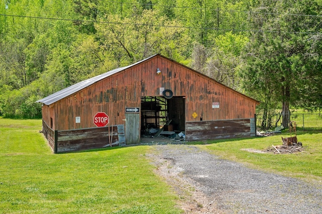 view of pole building featuring a yard, a wooded view, and fence