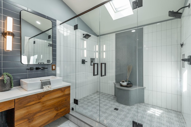 full bathroom with tile patterned flooring, vanity, tile walls, a stall shower, and vaulted ceiling with skylight