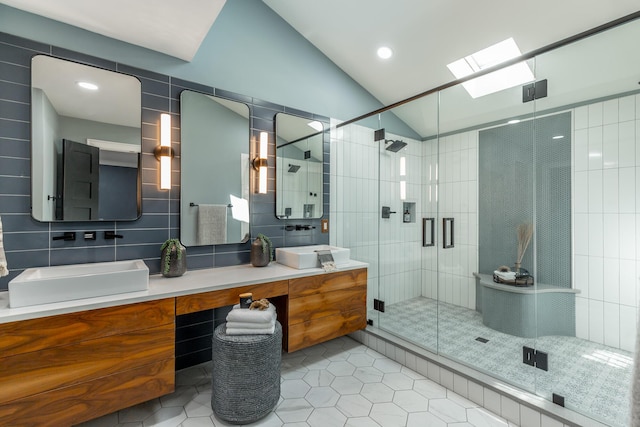 bathroom with a stall shower, tile walls, vaulted ceiling with skylight, tile patterned flooring, and double vanity