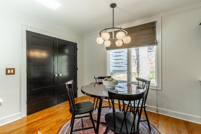 dining space with an inviting chandelier, ornamental molding, baseboards, and wood finished floors