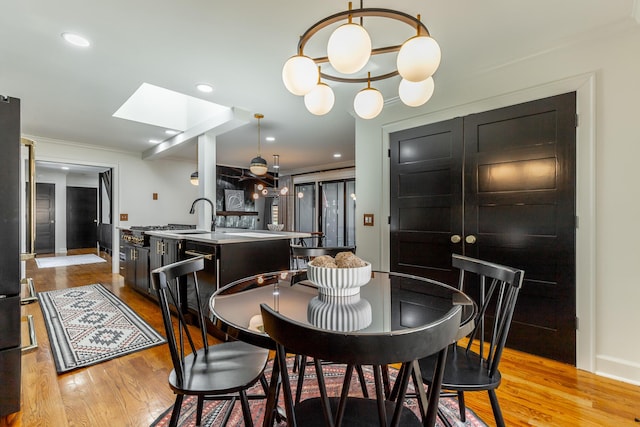 dining area with light wood-style flooring, a skylight, and recessed lighting