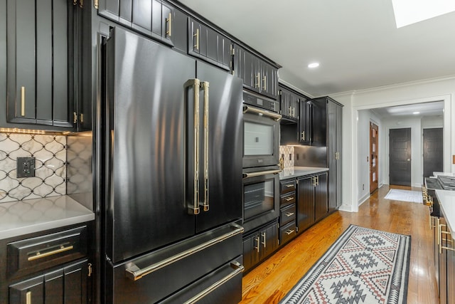 kitchen with decorative backsplash, baseboards, light wood-style floors, and high end refrigerator