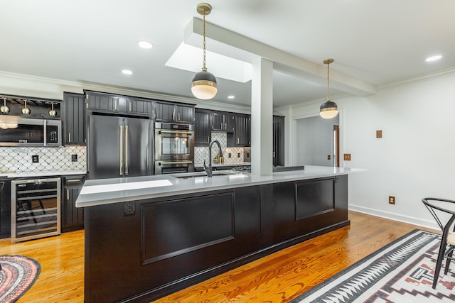 kitchen featuring crown molding, light wood-type flooring, wine cooler, pendant lighting, and appliances with stainless steel finishes