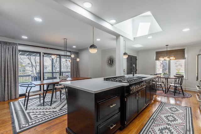 kitchen with a center island with sink, a wealth of natural light, stainless steel gas stovetop, and wood finished floors