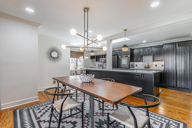 dining space with baseboards, crown molding, light wood-style flooring, and recessed lighting