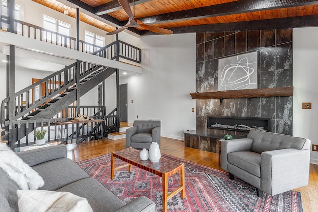 living area featuring baseboards, ceiling fan, wood finished floors, and wooden ceiling