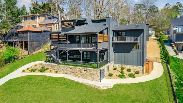 rear view of property with stairs, a garage, a deck, a lawn, and a shingled roof