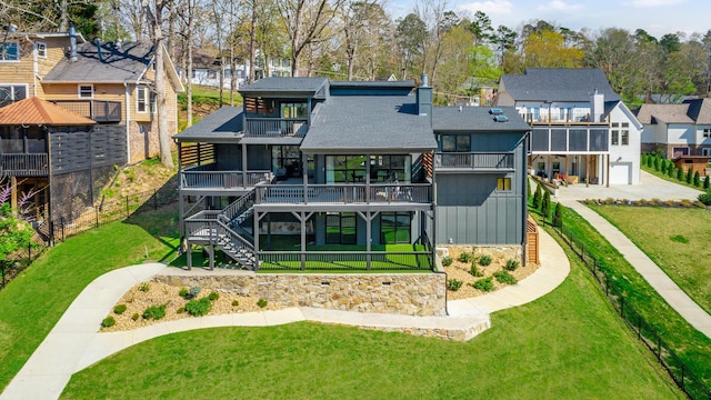 rear view of property featuring stairway, roof with shingles, a balcony, a residential view, and a yard
