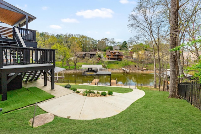 view of yard with stairs, a water view, fence, and a dock