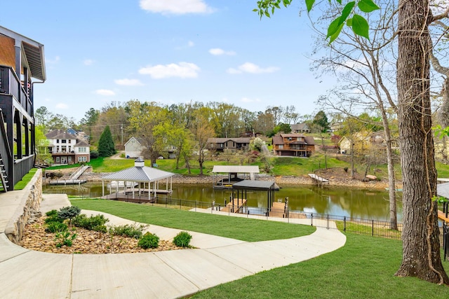 surrounding community featuring a boat dock, fence, a water view, and a yard