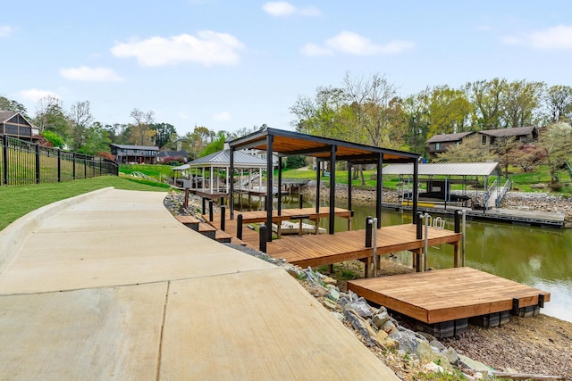 dock area featuring a water view, fence, and boat lift