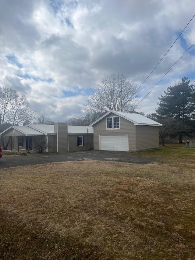 view of front facade with driveway, an outbuilding, and a front yard