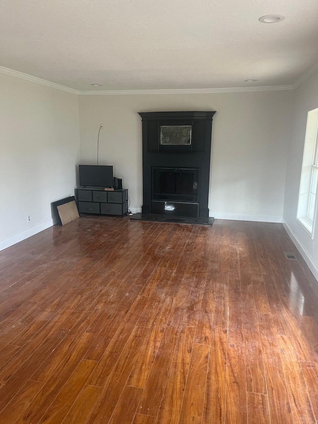unfurnished living room with dark wood-style flooring, crown molding, baseboards, and visible vents