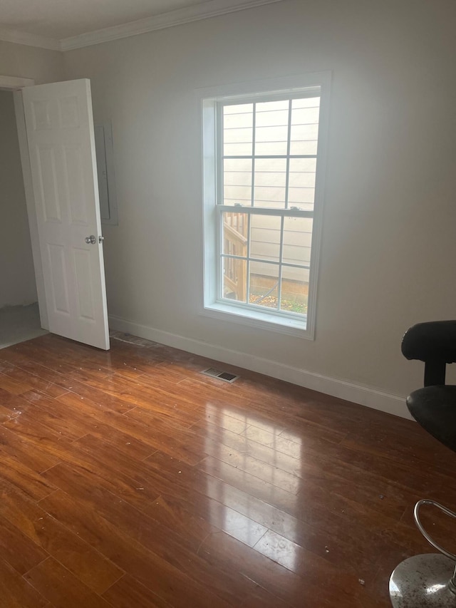 spare room with baseboards, visible vents, crown molding, and wood-type flooring