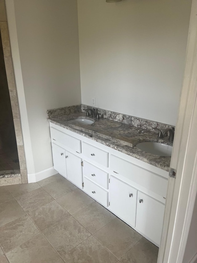 bathroom featuring double vanity, baseboards, a sink, and tile patterned floors