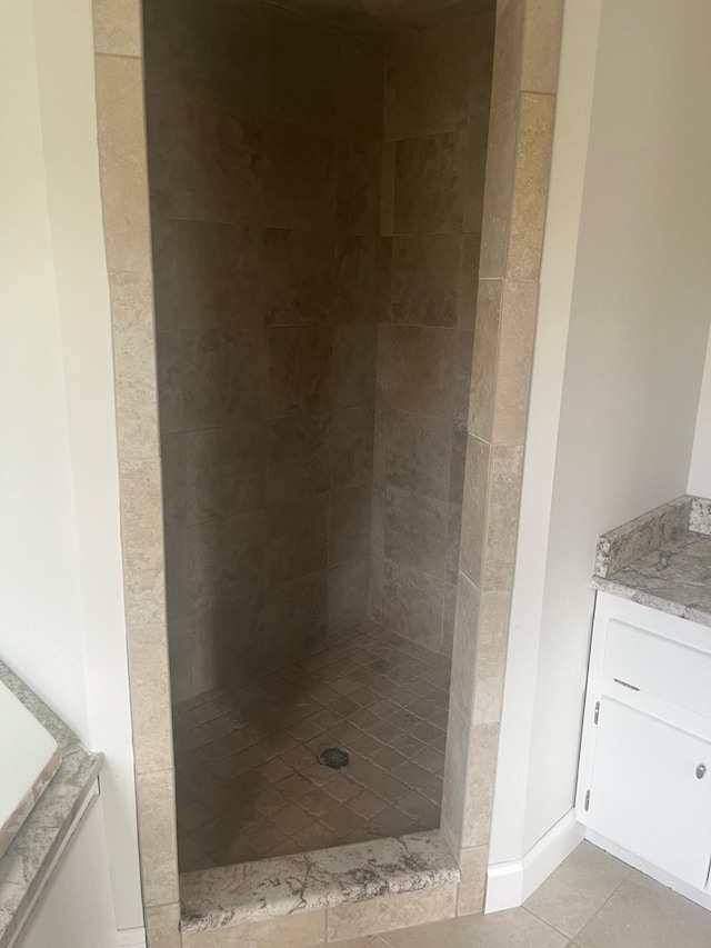 full bath featuring a tile shower, tile patterned flooring, and vanity