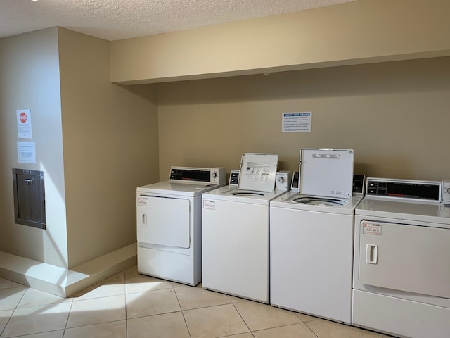 community laundry room featuring independent washer and dryer, a textured ceiling, and light tile patterned floors