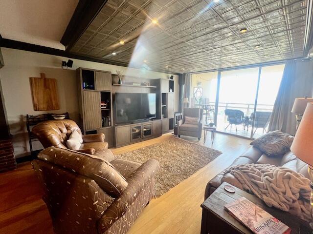 living area with an ornate ceiling, a wall of windows, and wood finished floors