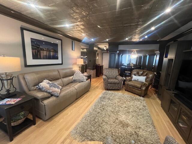 living area with ornamental molding and light wood-style flooring
