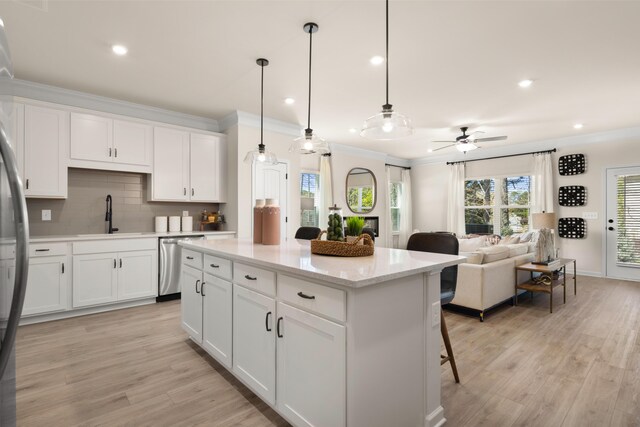 kitchen with decorative backsplash, dishwasher, ornamental molding, a sink, and light wood-type flooring