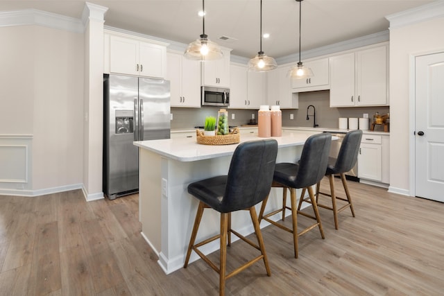kitchen featuring light countertops, crown molding, stainless steel appliances, and a kitchen island