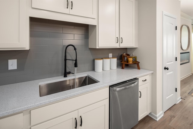 kitchen with stainless steel dishwasher, backsplash, a sink, white cabinets, and wood finished floors