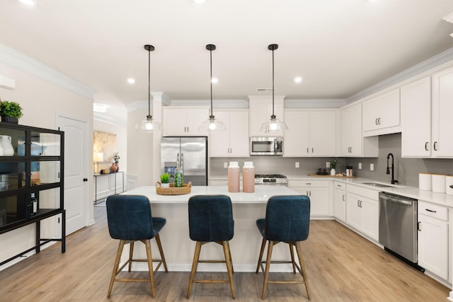kitchen with a breakfast bar, ornamental molding, stainless steel appliances, a kitchen island, and a sink