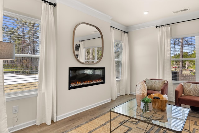living area with baseboards, visible vents, crown molding, and wood finished floors