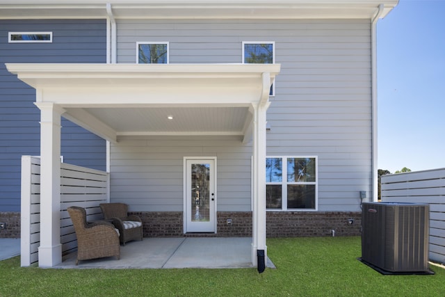 rear view of house featuring cooling unit, brick siding, a lawn, and a patio