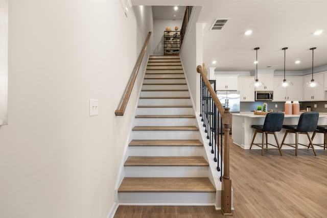 stairway featuring baseboards, visible vents, recessed lighting, and wood finished floors