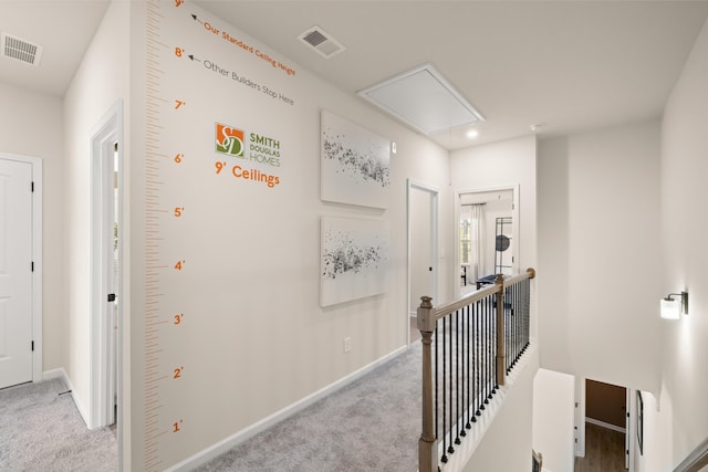 hall featuring light carpet, attic access, an upstairs landing, and visible vents