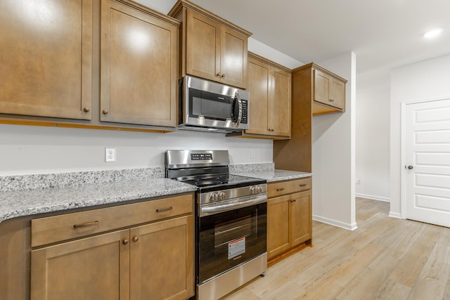 11304 Cape Vw, Soddy Daisy, TN 37379 - kitchen with appliances with stainless steel finishes, light wood-style flooring, light stone countertops, baseboards, and brown cabinetry
