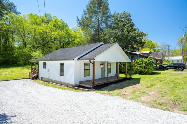view of front of house with a front yard, a porch, gravel driveway, and a shingled roof