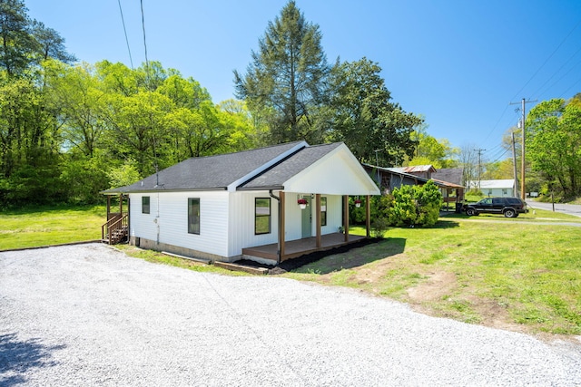 view of front facade with a front yard, a porch, a shingled roof, and driveway