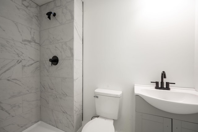 bathroom featuring vanity, a tile shower, and toilet