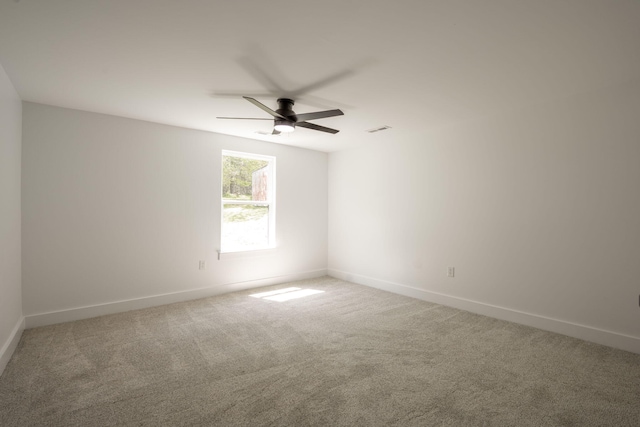 spare room with baseboards, light colored carpet, ceiling fan, and visible vents