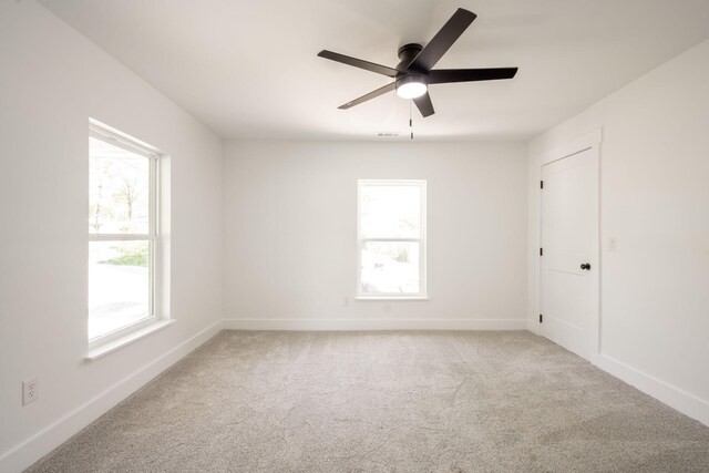 unfurnished room with carpet, visible vents, baseboards, and ceiling fan