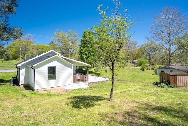 view of side of home featuring a yard, an outdoor structure, and cooling unit
