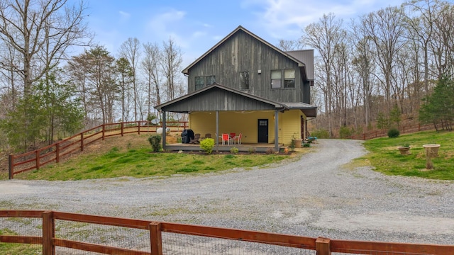 view of front of home with driveway, covered porch, and fence