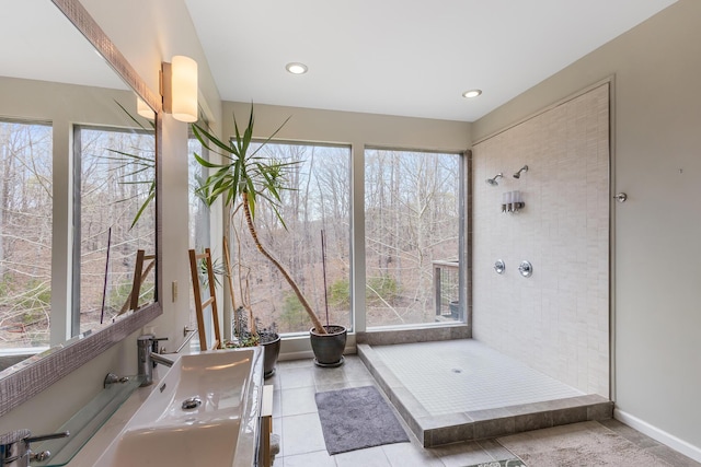 bathroom featuring tile patterned floors, a tile shower, vanity, baseboards, and recessed lighting