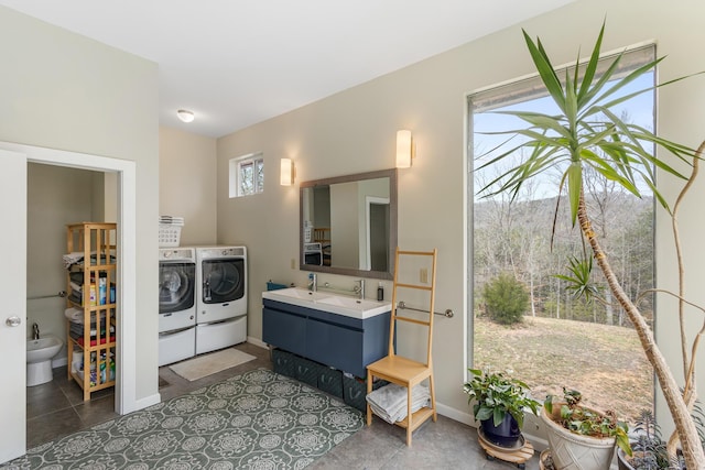 bathroom featuring washing machine and clothes dryer, vanity, baseboards, and a bidet