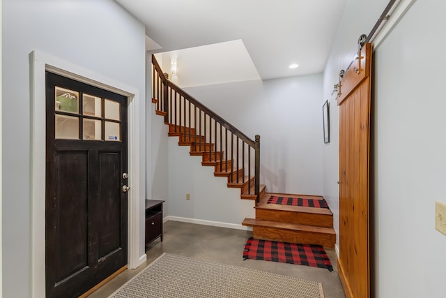 entryway featuring baseboards, stairway, recessed lighting, a barn door, and concrete flooring