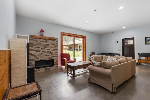 living area featuring a stone fireplace, recessed lighting, and finished concrete floors