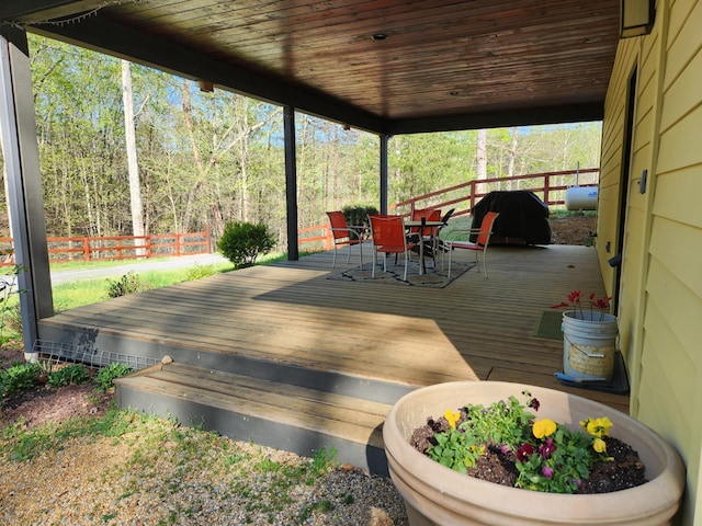 wooden deck with outdoor dining space and area for grilling
