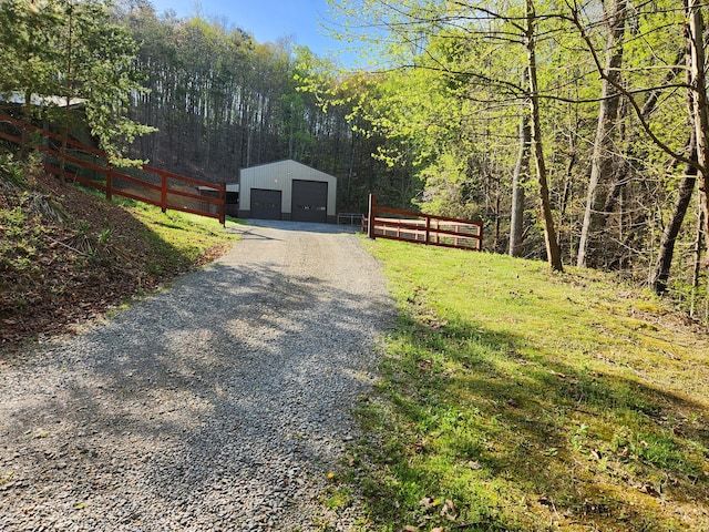 exterior space with an outbuilding, fence, a forest view, and a detached garage