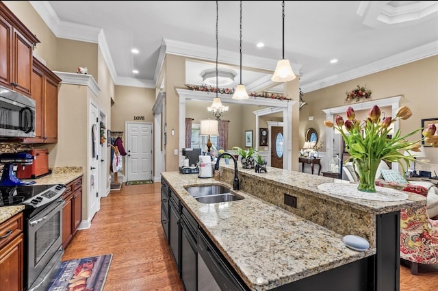 kitchen featuring a notable chandelier, a sink, light wood finished floors, a center island with sink, and stainless steel appliances