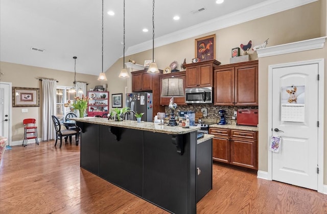 kitchen with a kitchen breakfast bar, light wood-style flooring, appliances with stainless steel finishes, and visible vents