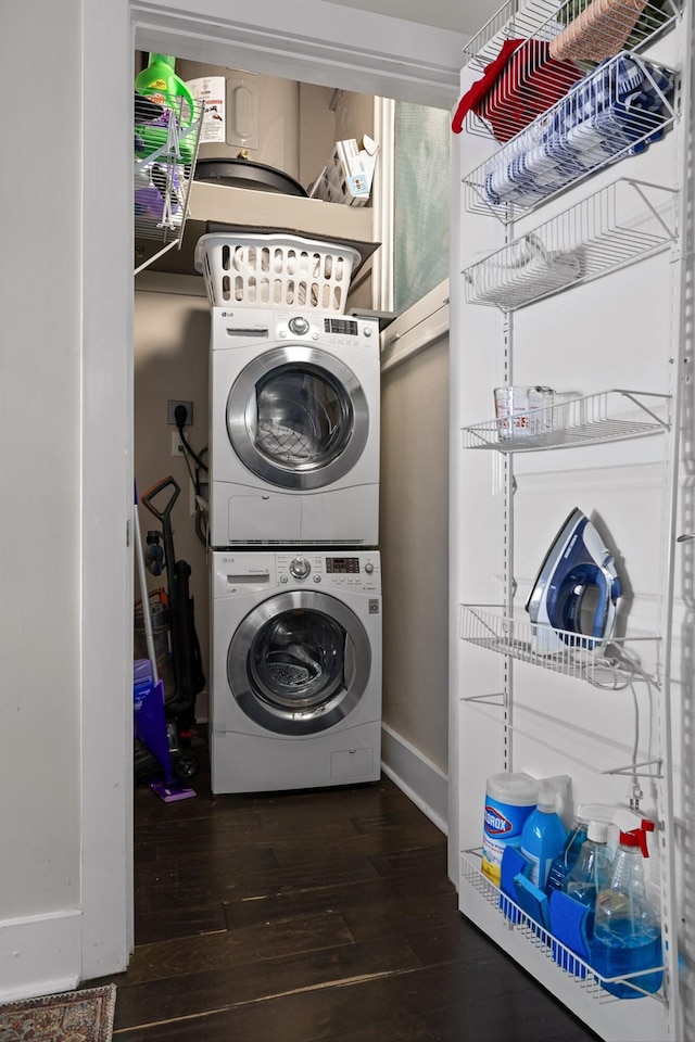 laundry area featuring stacked washer / dryer, hardwood / wood-style flooring, and laundry area