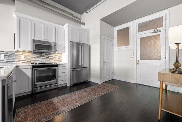 kitchen with decorative backsplash, light countertops, stainless steel appliances, and dark wood finished floors