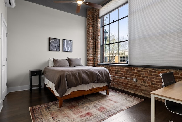 bedroom with multiple windows, an AC wall unit, brick wall, and dark wood-type flooring